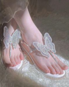 Close up of feet wearing sparkling butterfly sandals on a white fur rug