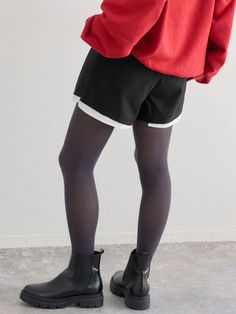 Person in a red hoodie, black shorts, and tights with black boots