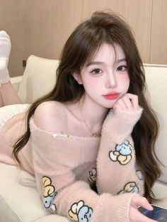 Woman with long hair wearing a pink off-shoulder fluffy sweater with cartoon prints