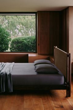 Bedroom with dark bedding and a large window overlooking a garden