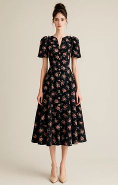 Woman in a black floral dress with an updo posing in a studio