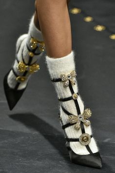 Close up of feet in black high heels with white socks and gold bows