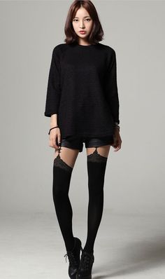 Woman in a black top, shorts, and thigh-high stockings with lace trim