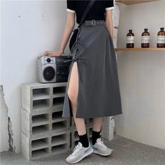 Person in a black top and gray midi skirt with a high slit standing next to a boombox