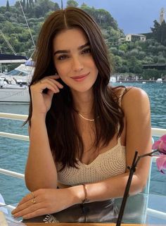Woman with long brown hair wearing a crochet top by a lake