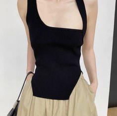 Person wearing a black asymmetrical ribbed top and khaki pants