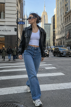 Woman in a leather jacket and jeans walking on a city street