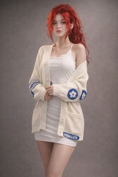 Woman with red hair and freckles wearing a white dress and cardigan indoors