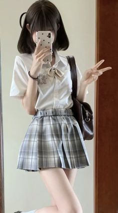 Person in a school uniform taking a mirror selfie with a peace sign