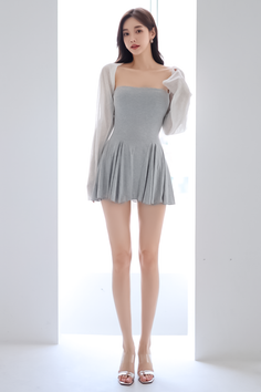 Woman in a gray dress and white cardigan standing indoors
