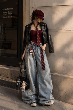 Woman in a red cap, leather jacket, and wide leg jeans holding a black handbag