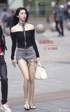Woman in an off-shoulder top and denim shorts walking on a street
