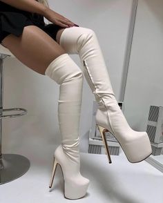 Person wearing thigh-high platform boots and a short skirt while sitting