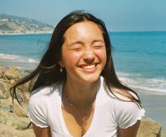 Woman with long hair smiling with eyes closed on a sunny beach