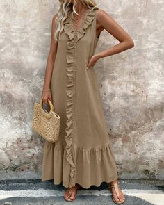 Woman in a long brown maxi dress with ruffle trim holding a straw bag