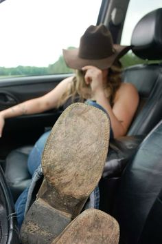 Person in a cowboy hat and boots resting in a car with feet up