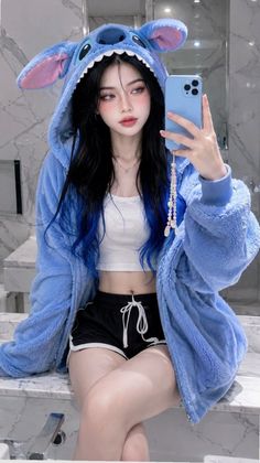 Woman in a blue hoodie and crop top taking a mirror selfie