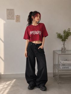 Woman in a red crop top and baggy black jeans with a ponytail and red hair streaks