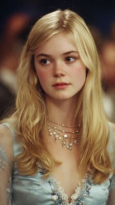 Young woman with blonde hair wearing a blue dress and layered necklace