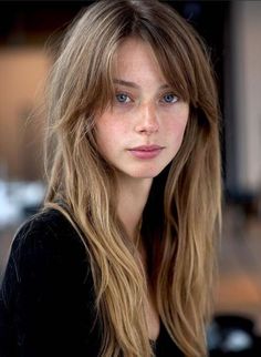 Woman with long hair, blue eyes, and freckles looking directly at the viewer