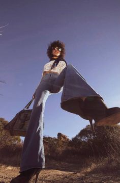Woman with curly hair and sunglasses in bell bottom jeans and heeled boots