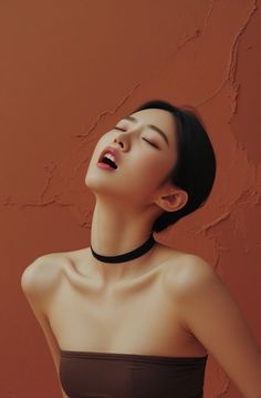 Woman with short hair and a choker in a provocative pose against a brown wall