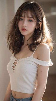 Woman with long wavy hair wearing a white top with exposed shoulders and midriff