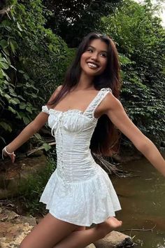 Woman in a white dress smiling in a forest setting