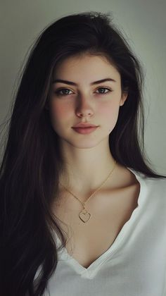 Young woman with long dark hair wearing a white shirt and heart necklace
