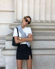 Woman in a black mini skirt and white polo shirt posing outdoors