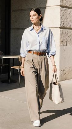 Woman in a light blue shirt and wide leg pants walking outdoors