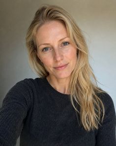 Woman with blonde hair and blue eyes wearing a dark sweater, looking at the camera