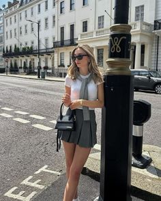Woman in a pleated skirt and white top standing on a city street