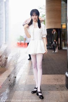 Woman in a white dress and white stockings with pigtails standing outdoors