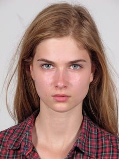 Young woman with long hair and blue eyes wearing a red plaid shirt