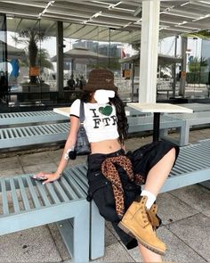 Woman in a crop top and cargo pants with a leopard print scarf, sitting outdoors