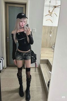 Woman in a black off-shoulder top and denim shorts taking a mirror selfie