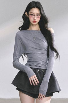 Woman with long black hair wearing an off-shoulder top and mini skirt