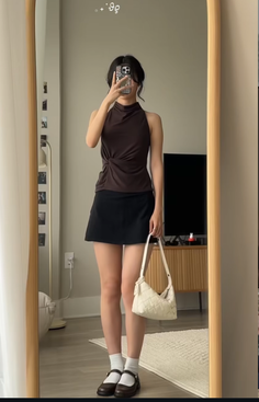 Woman in a dark halter top and black mini skirt taking a mirror selfie
