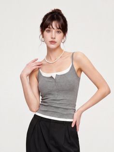 Woman in a gray tank top and black pants with a pearl necklace in a studio