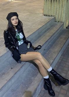 Woman in a black beret and leather jacket sitting on outdoor steps at night