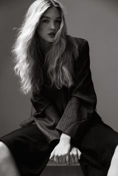 Woman with long blonde hair wearing a blazer in a black and white studio portrait