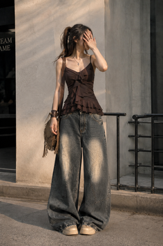 Woman in a brown ruffle top and wide leg jeans outdoors at golden hour