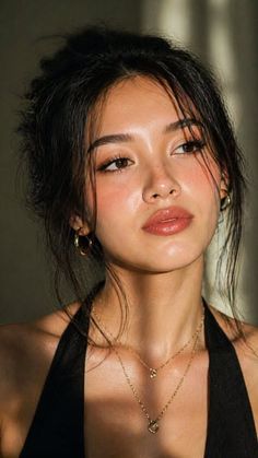 Woman with a messy bun and gold jewelry in soft, warm lighting