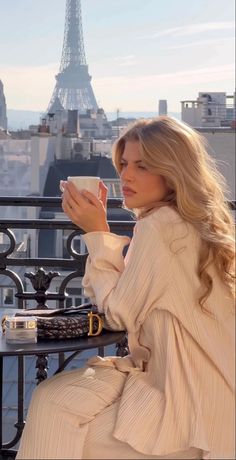 Woman with long blonde hair on a balcony overlooking the Eiffel Tower