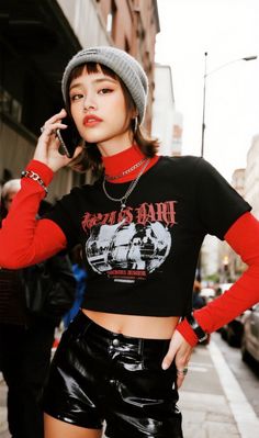 Woman in a beanie, red turtleneck, and leather shorts on a city street