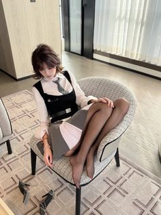 Woman with short hair wearing a vest and tie, sitting indoors