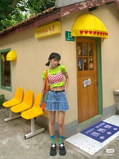 Young woman in a denim skirt and crop top standing outside a building