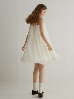 Woman in a white dress with ruffle trim and white socks indoors