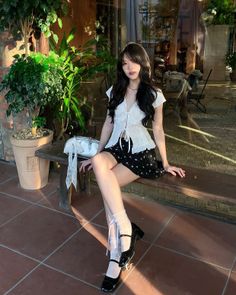 Woman with long black hair sitting on a bench outdoors in soft lighting